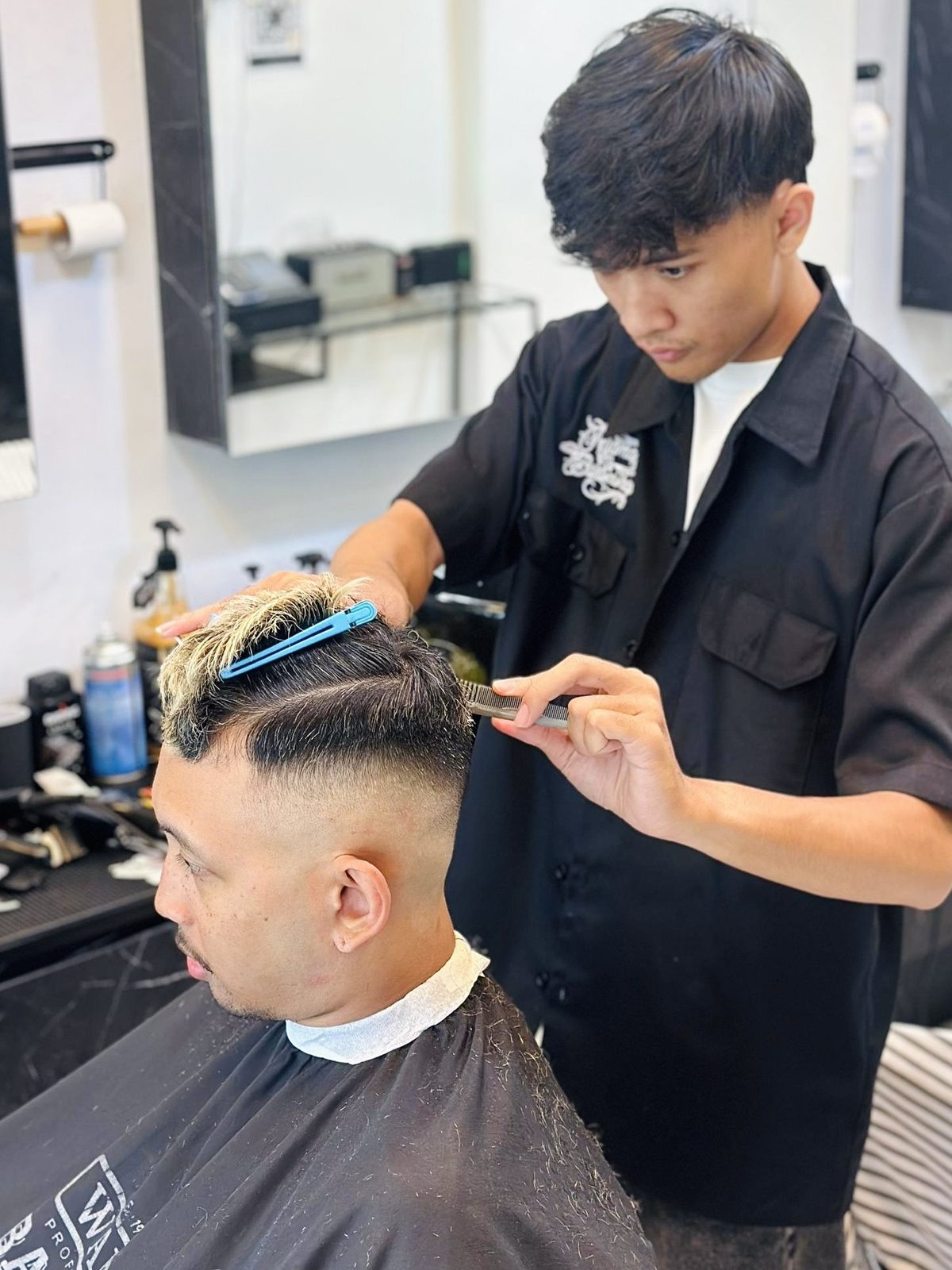A barber mid-cut with clippers