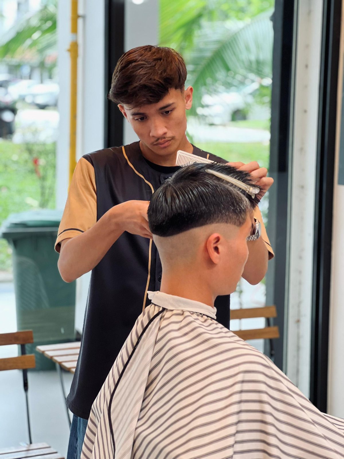 A barber cutting by the window in daylight